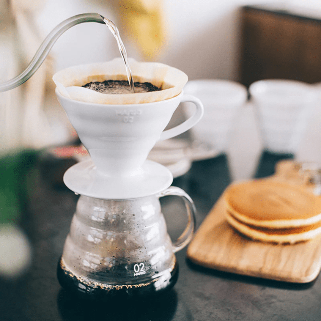 Mit der Glasskanne und einem V60 Dripper wird frischer Kaffee gekocht.