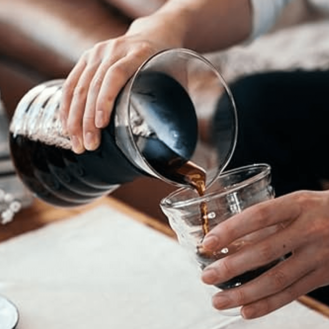Jemand benutzt den Hario Drip Decanter als Karaffe und füllt frisch gekochten Kaffee in ein Glas